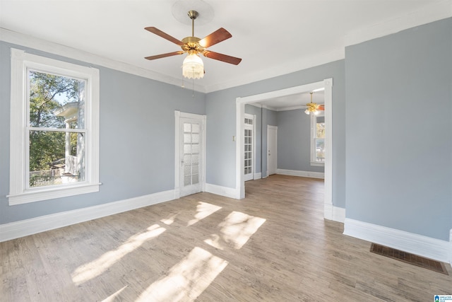 empty room with a wealth of natural light, crown molding, and hardwood / wood-style flooring