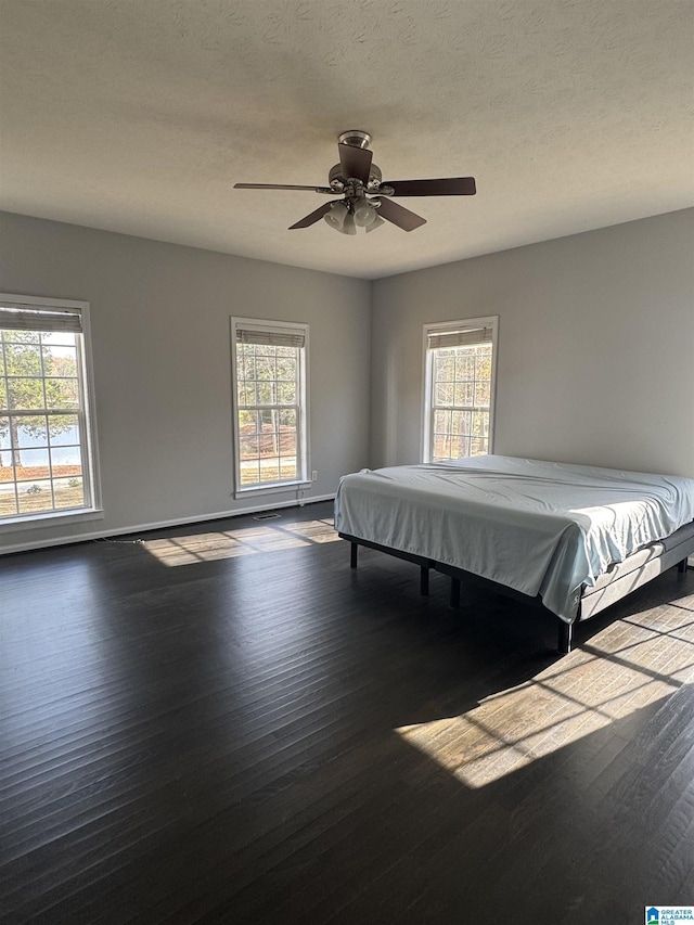 unfurnished bedroom with ceiling fan, dark hardwood / wood-style flooring, billiards, and multiple windows