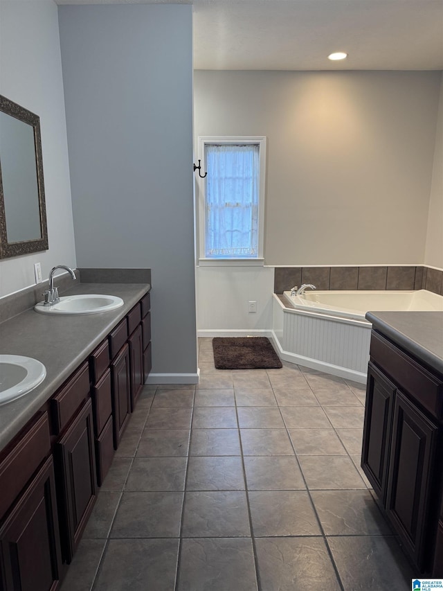 bathroom with a washtub, vanity, and tile patterned floors