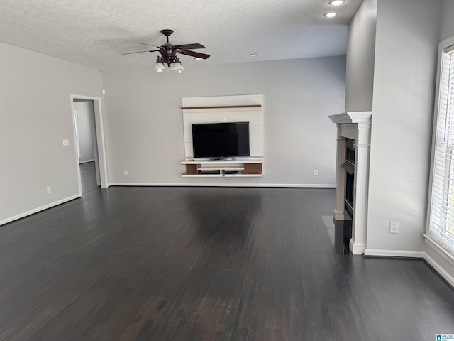 unfurnished living room with a textured ceiling, dark hardwood / wood-style flooring, and ceiling fan