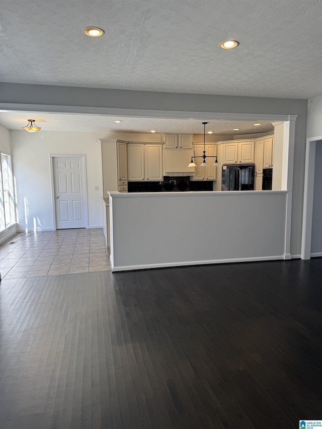 kitchen with decorative light fixtures, light hardwood / wood-style flooring, black appliances, and a textured ceiling