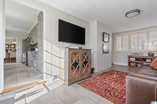 living room featuring ornamental molding and brick wall