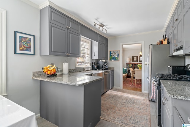 kitchen featuring light stone countertops, ornamental molding, stainless steel appliances, sink, and gray cabinets