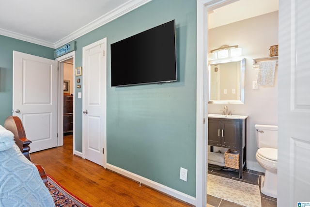 bedroom with hardwood / wood-style floors, crown molding, and sink