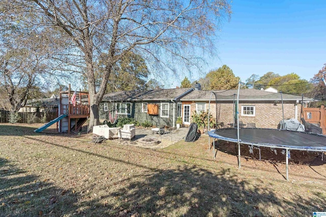 back of property featuring a playground, a lawn, and a trampoline