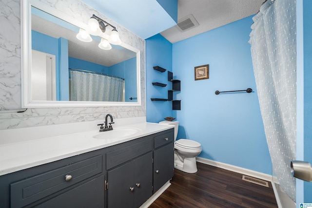 bathroom featuring vanity, a textured ceiling, wood-type flooring, toilet, and curtained shower