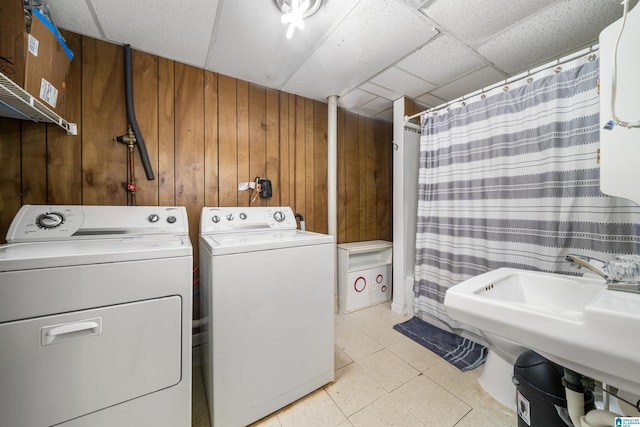 washroom featuring washer and dryer, wooden walls, and sink