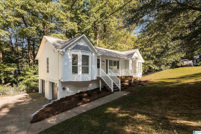 view of front of property featuring a porch, a garage, and a front lawn