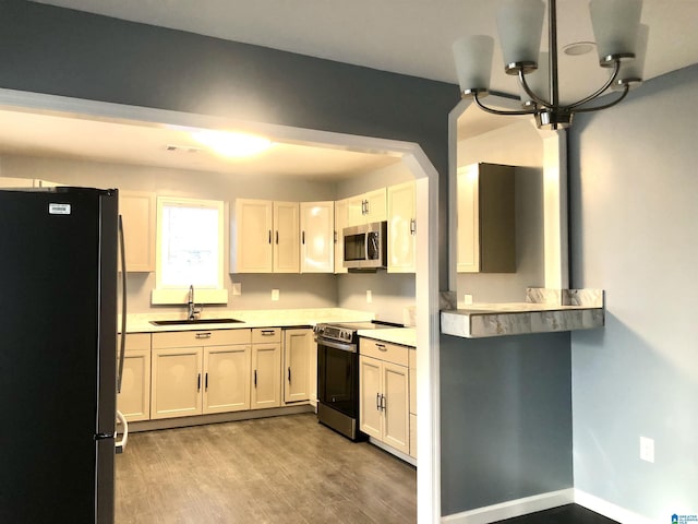 kitchen featuring white cabinetry, sink, black fridge, range with electric stovetop, and light wood-type flooring