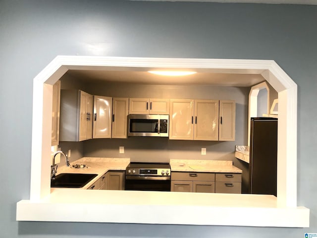 kitchen with light brown cabinetry, sink, and stainless steel appliances