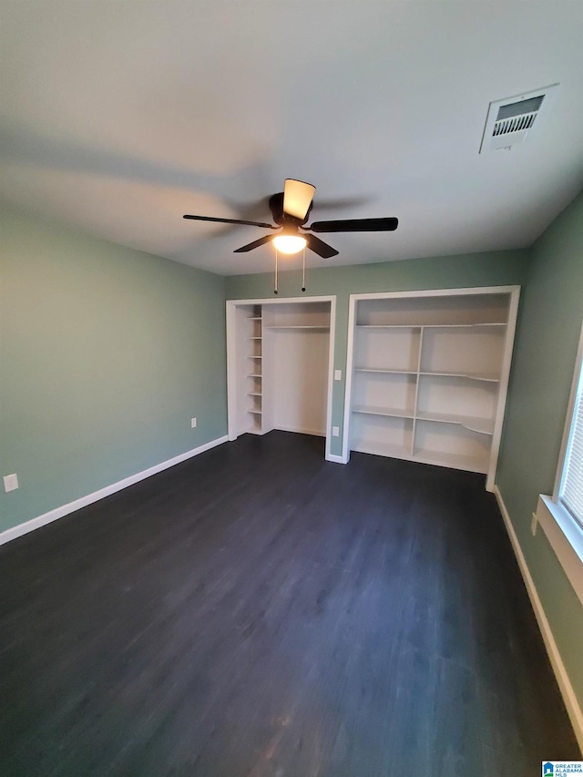 1245 16th St SW, Birmingham, AL 35211 - unfurnished bedroom featuring dark wood-type flooring, baseboards, ceiling fan, and multiple closets