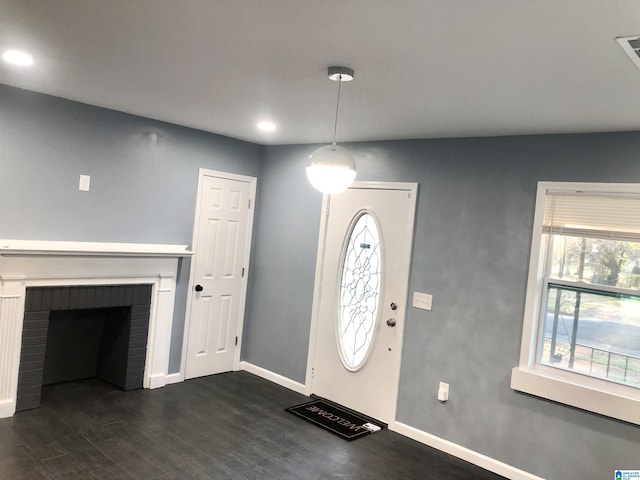 foyer entrance with a fireplace and dark wood-type flooring