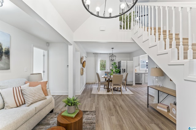 living room featuring hardwood / wood-style flooring, lofted ceiling, and an inviting chandelier