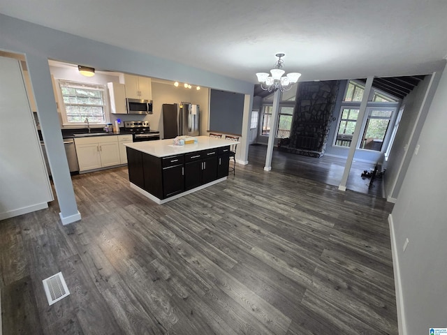 kitchen with dark wood-type flooring, sink, appliances with stainless steel finishes, a kitchen island, and white cabinetry