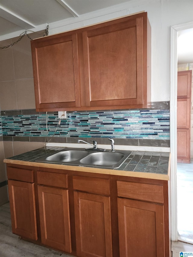 kitchen featuring backsplash, tile countertops, light hardwood / wood-style flooring, and sink