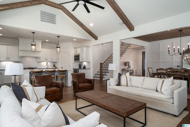 living room featuring beam ceiling, sink, high vaulted ceiling, light hardwood / wood-style floors, and ceiling fan with notable chandelier