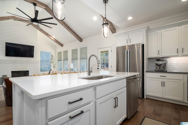 kitchen with sink, dark wood-type flooring, stainless steel appliances, lofted ceiling with beams, and an island with sink