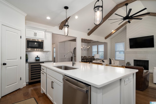 kitchen with stainless steel appliances, a kitchen island with sink, sink, white cabinets, and wine cooler