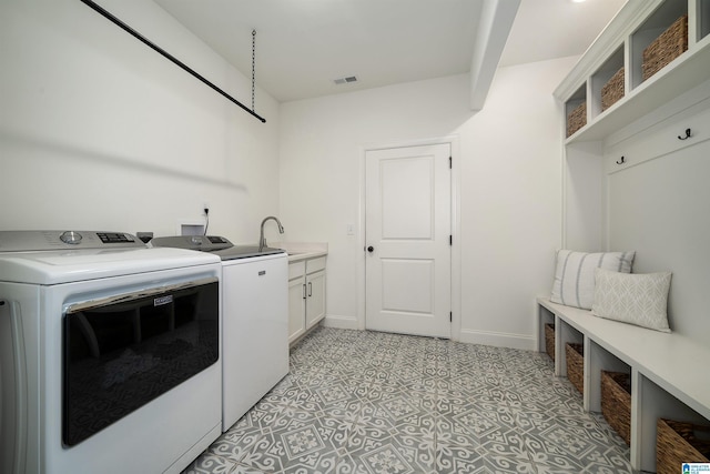 laundry room featuring cabinets, independent washer and dryer, and sink