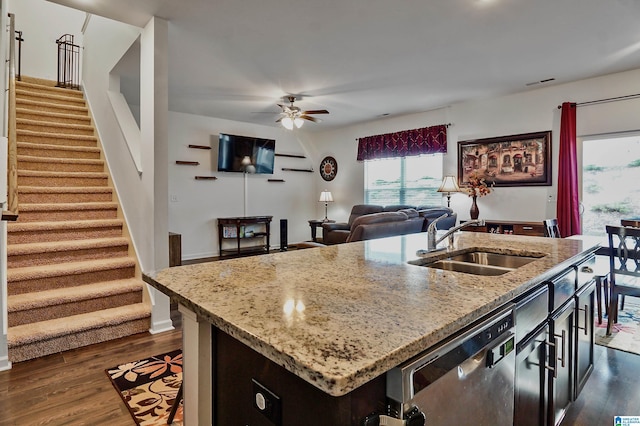 kitchen featuring dishwasher, sink, a kitchen island with sink, and dark wood-type flooring