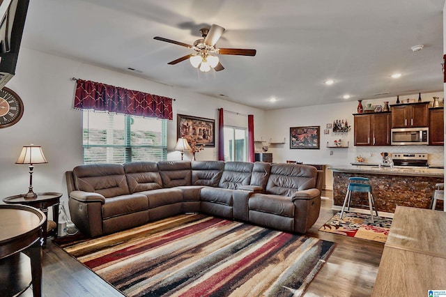 living room with ceiling fan and dark wood-type flooring