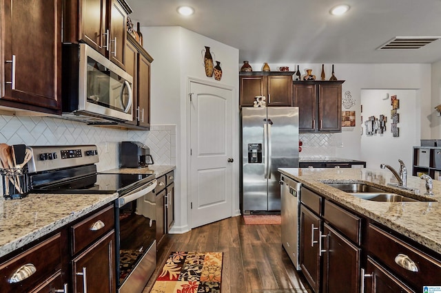 kitchen with light stone countertops, sink, dark hardwood / wood-style flooring, decorative backsplash, and appliances with stainless steel finishes