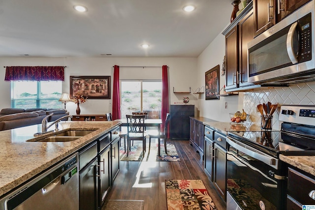 kitchen featuring sink, stainless steel appliances, tasteful backsplash, light stone counters, and dark hardwood / wood-style floors