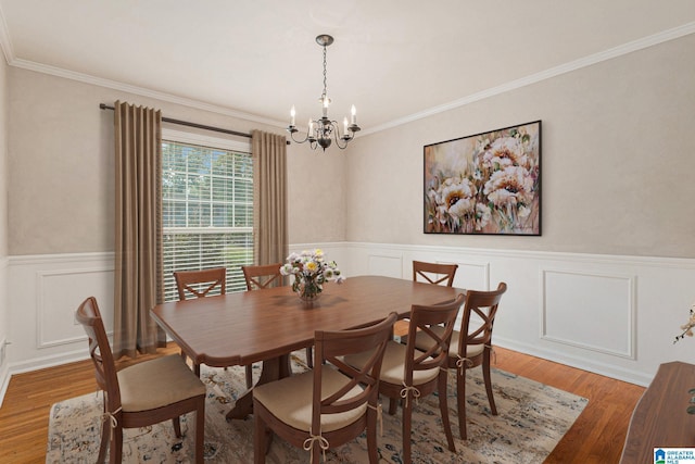 dining area with ornamental molding, a chandelier, and wood-type flooring