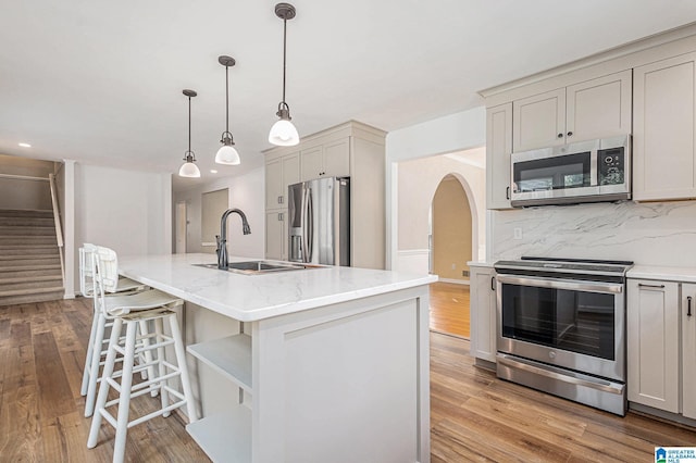 kitchen featuring stainless steel appliances, a kitchen island with sink, and light hardwood / wood-style floors