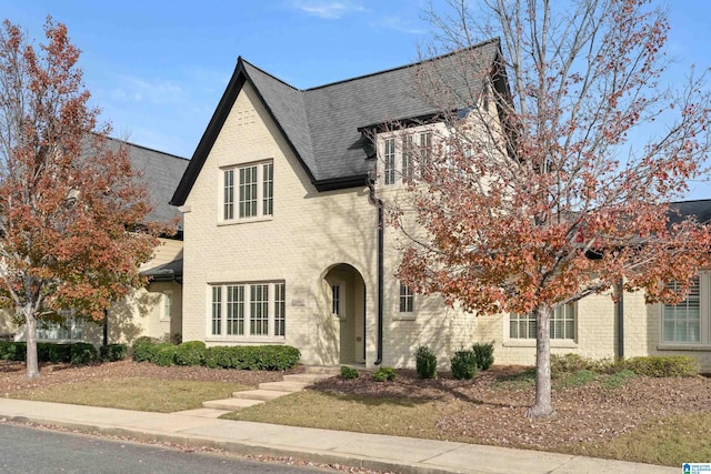 tudor-style house featuring a front lawn