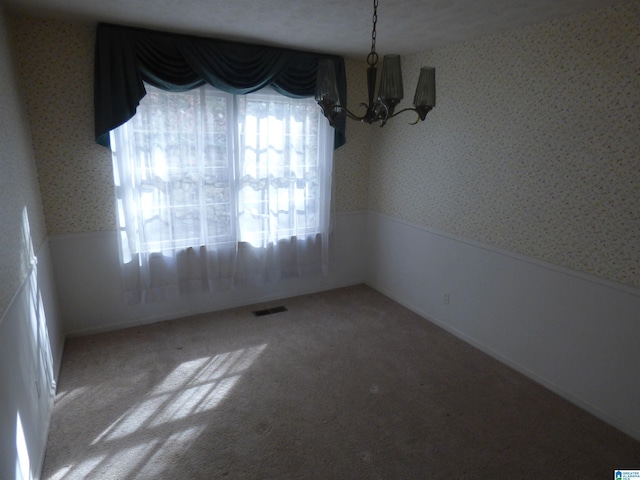 unfurnished dining area featuring plenty of natural light, carpet floors, a textured ceiling, and an inviting chandelier