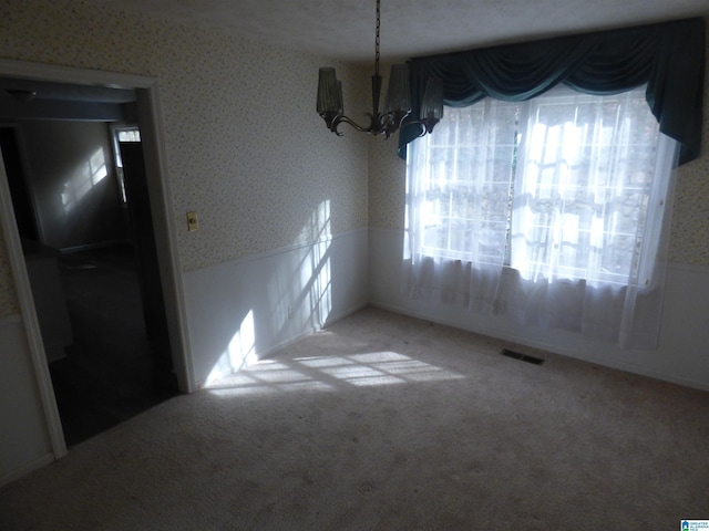 unfurnished dining area featuring a chandelier, a textured ceiling, and carpet floors