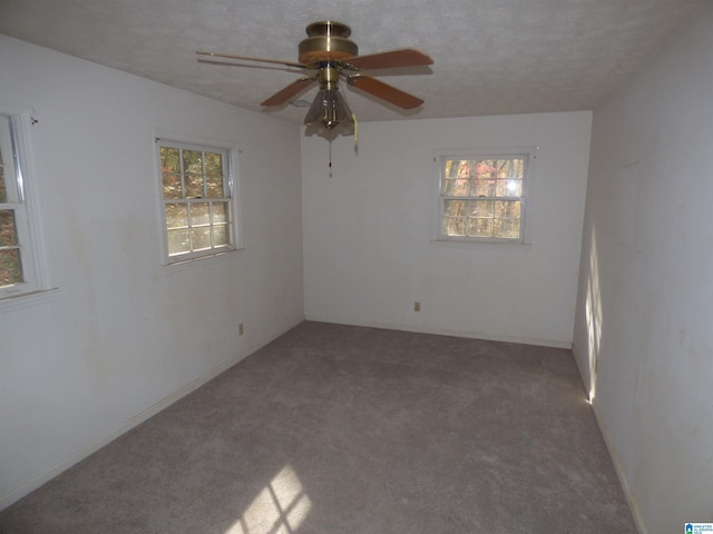 carpeted spare room featuring ceiling fan and a textured ceiling