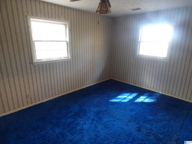 carpeted empty room featuring a wealth of natural light and ceiling fan