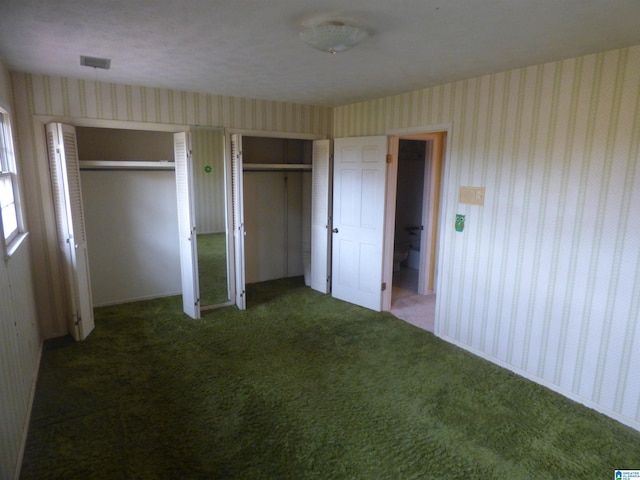 unfurnished bedroom featuring dark colored carpet and two closets