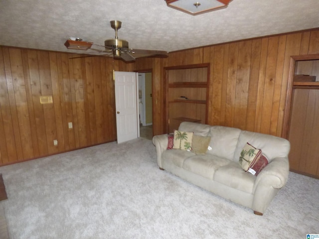 unfurnished living room with wood walls, ceiling fan, light carpet, and a textured ceiling