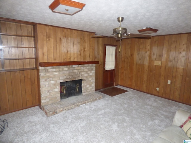 unfurnished living room with wooden walls, light colored carpet, a textured ceiling, and a brick fireplace