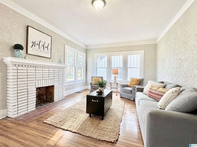 living room featuring hardwood / wood-style flooring, ornamental molding, and a brick fireplace