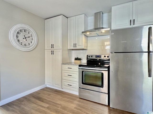 kitchen featuring white cabinets, wall chimney exhaust hood, decorative backsplash, light wood-type flooring, and stainless steel appliances