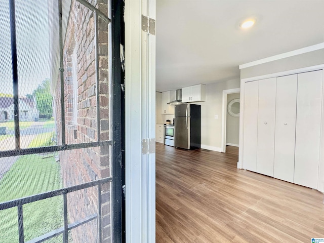 interior space featuring wall chimney range hood, appliances with stainless steel finishes, and wood-type flooring