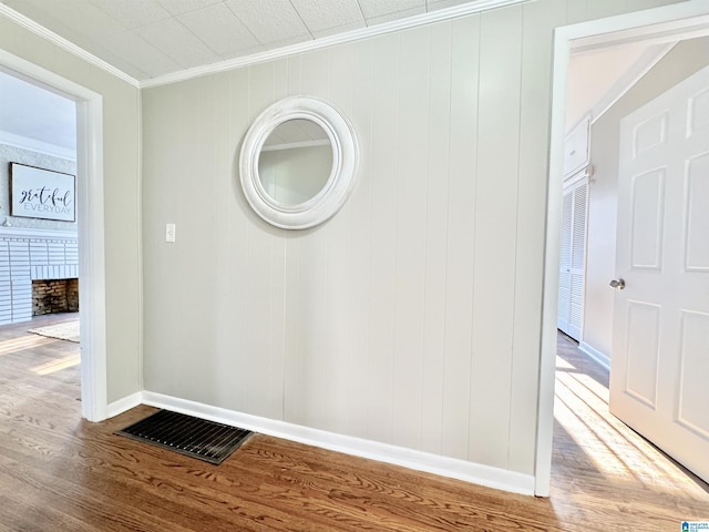 interior details with wooden walls, hardwood / wood-style flooring, a brick fireplace, and ornamental molding