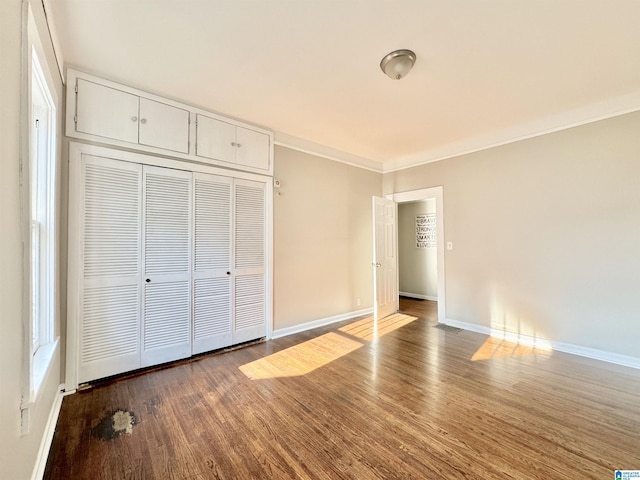 unfurnished bedroom with ornamental molding, a closet, and dark wood-type flooring