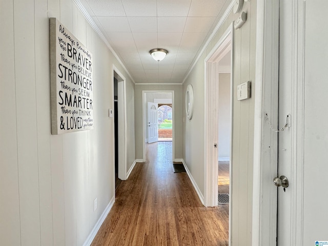 hallway with wood-type flooring, ornamental molding, and wood walls