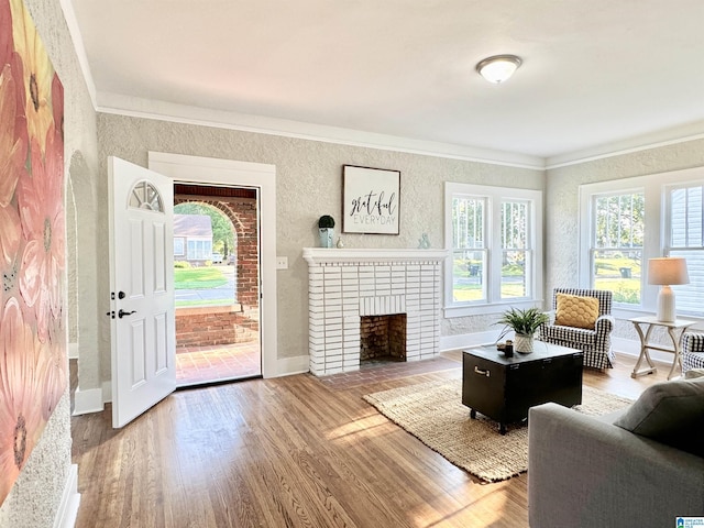 living room featuring hardwood / wood-style floors, crown molding, and a brick fireplace