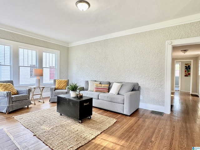 living room featuring a healthy amount of sunlight, wood-type flooring, and crown molding