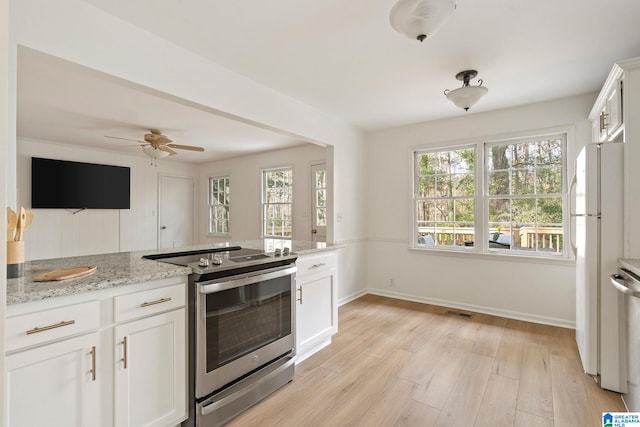 kitchen with light stone counters, white fridge, white cabinets, light hardwood / wood-style floors, and stainless steel electric range