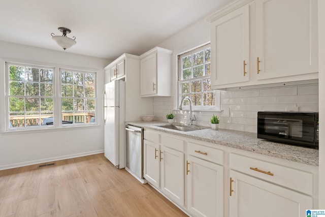 kitchen featuring sink, dishwasher, white refrigerator, backsplash, and white cabinets