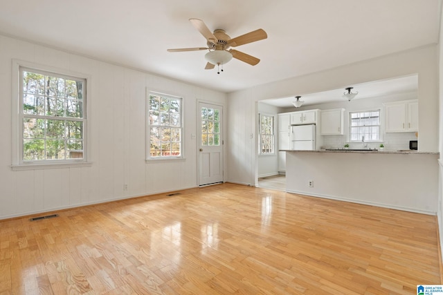 unfurnished living room featuring ceiling fan and light hardwood / wood-style floors