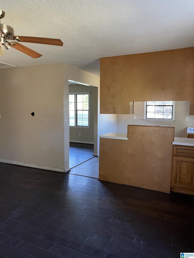 unfurnished room featuring ceiling fan, dark wood-type flooring, and a textured ceiling