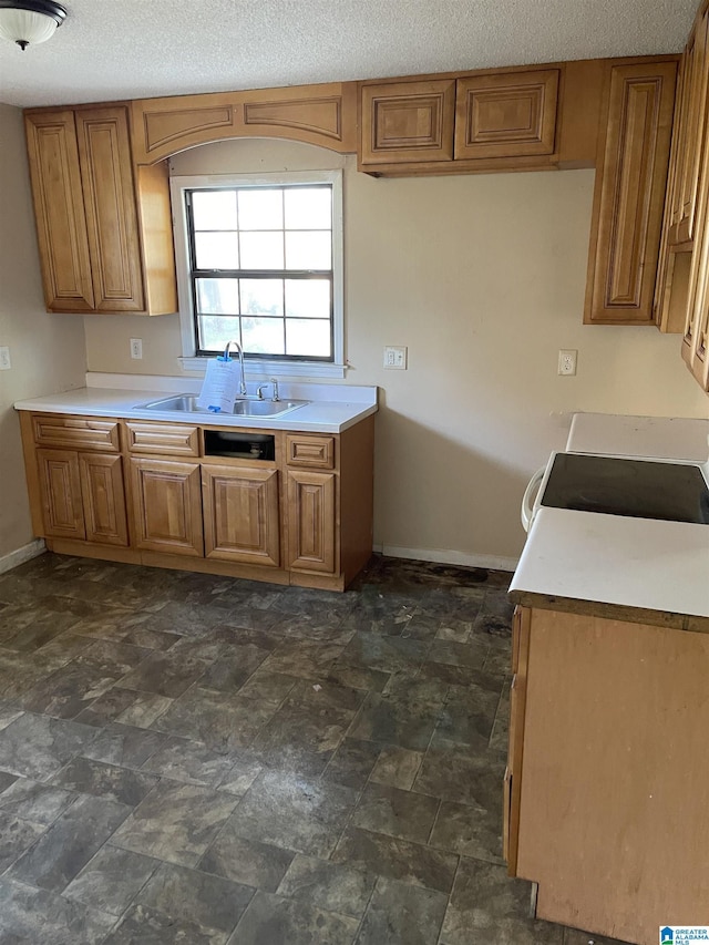 kitchen featuring range, a textured ceiling, and sink